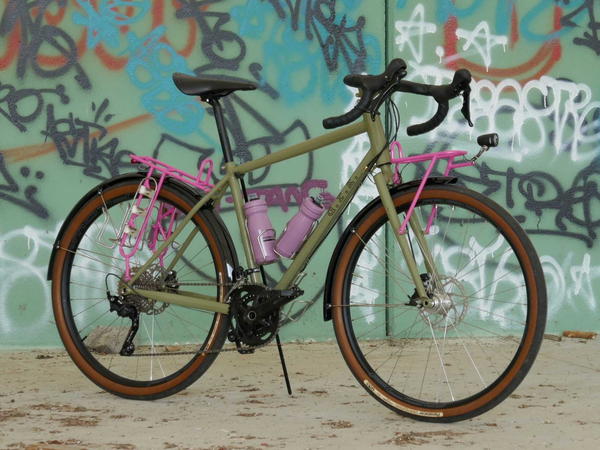 green gravel bike with pink racks and water bottles