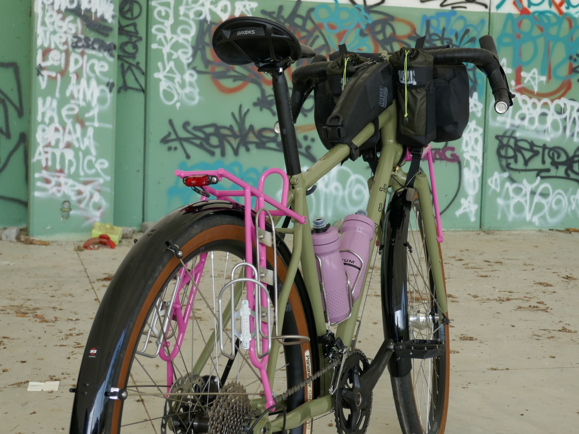 green gravel bike with pink racks viewd from behind