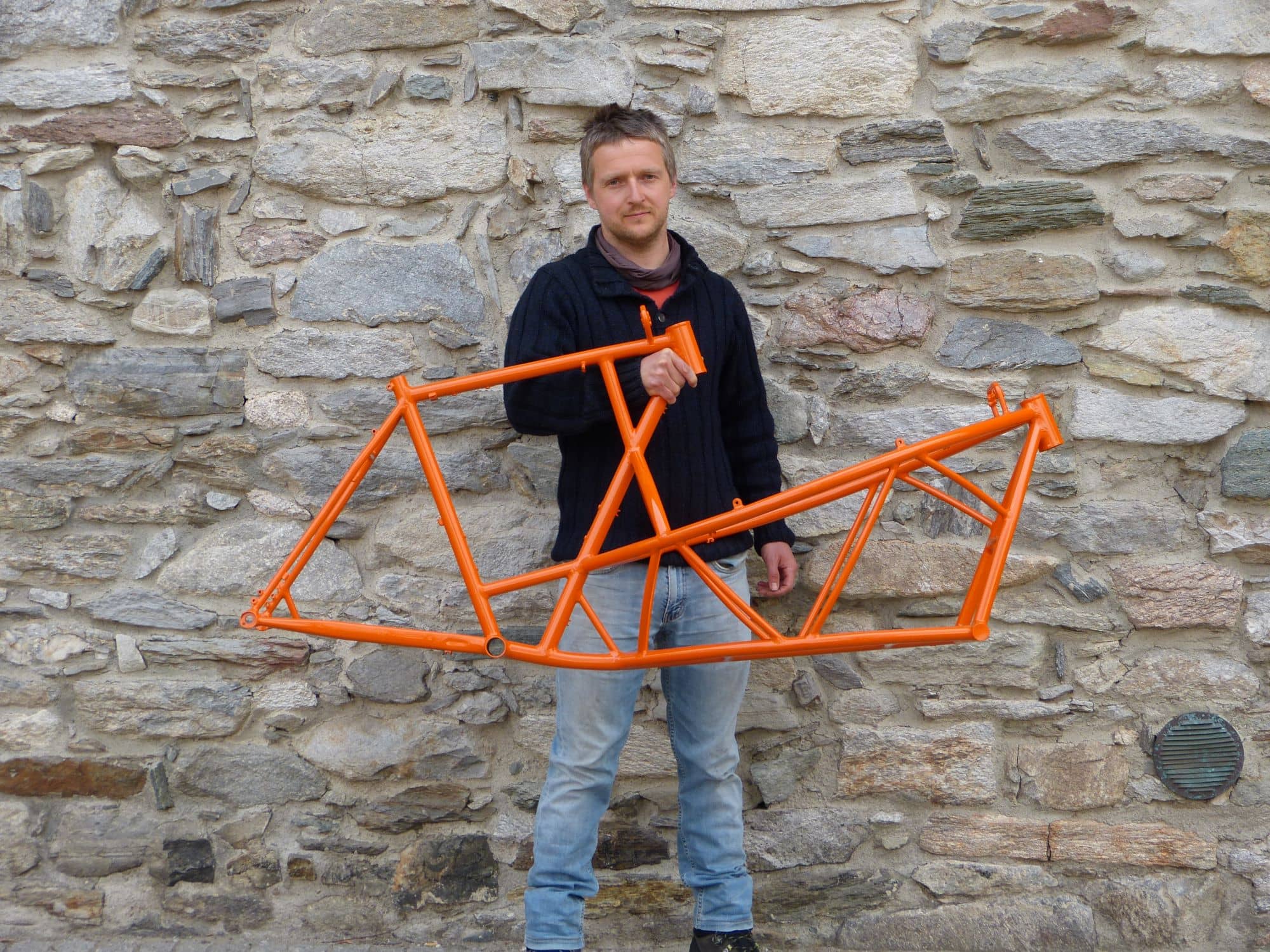 Daniel holding the frame of an orange cargo bike