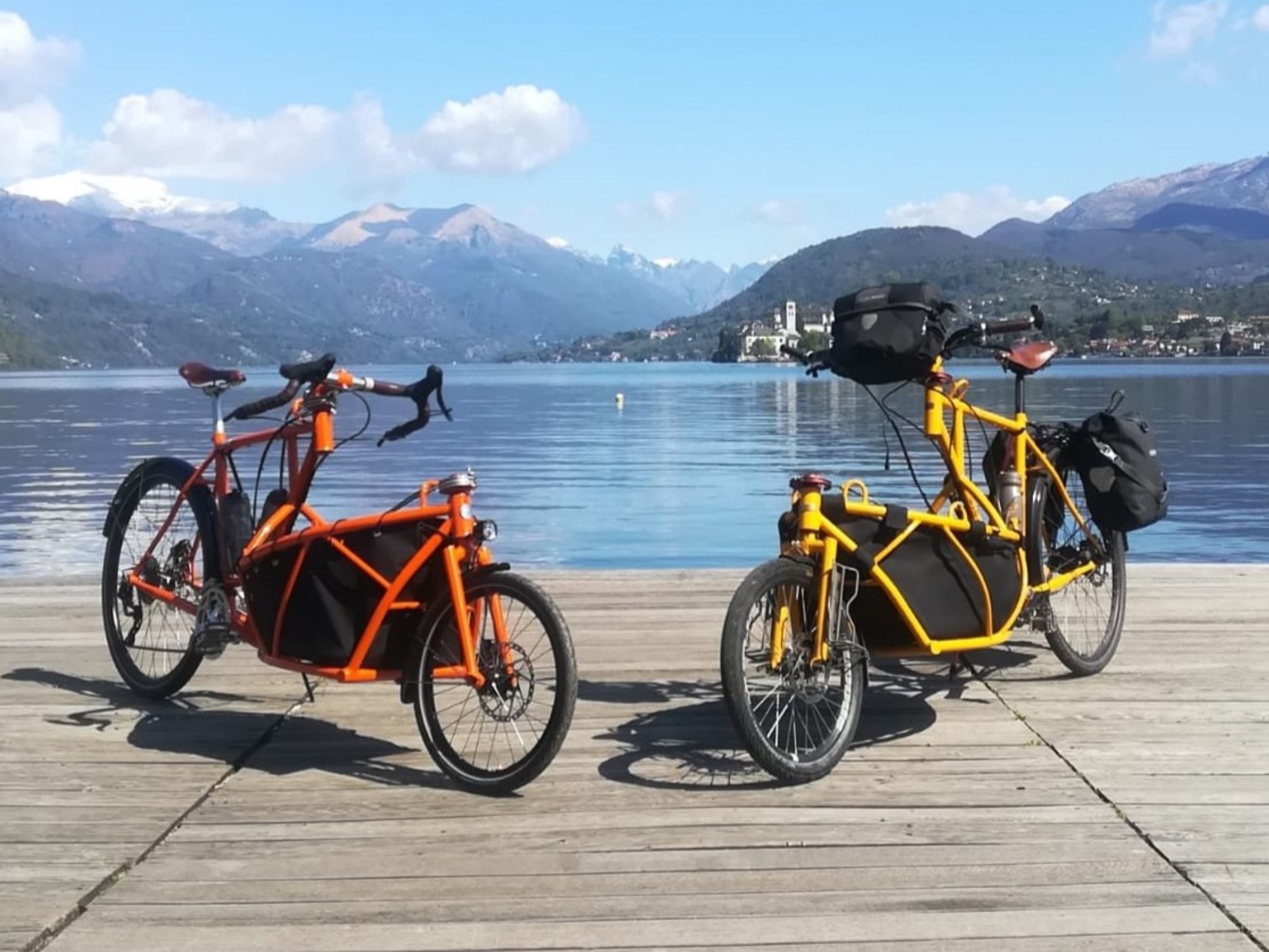 orange and yellow cargo bikes with lake Orta in the background